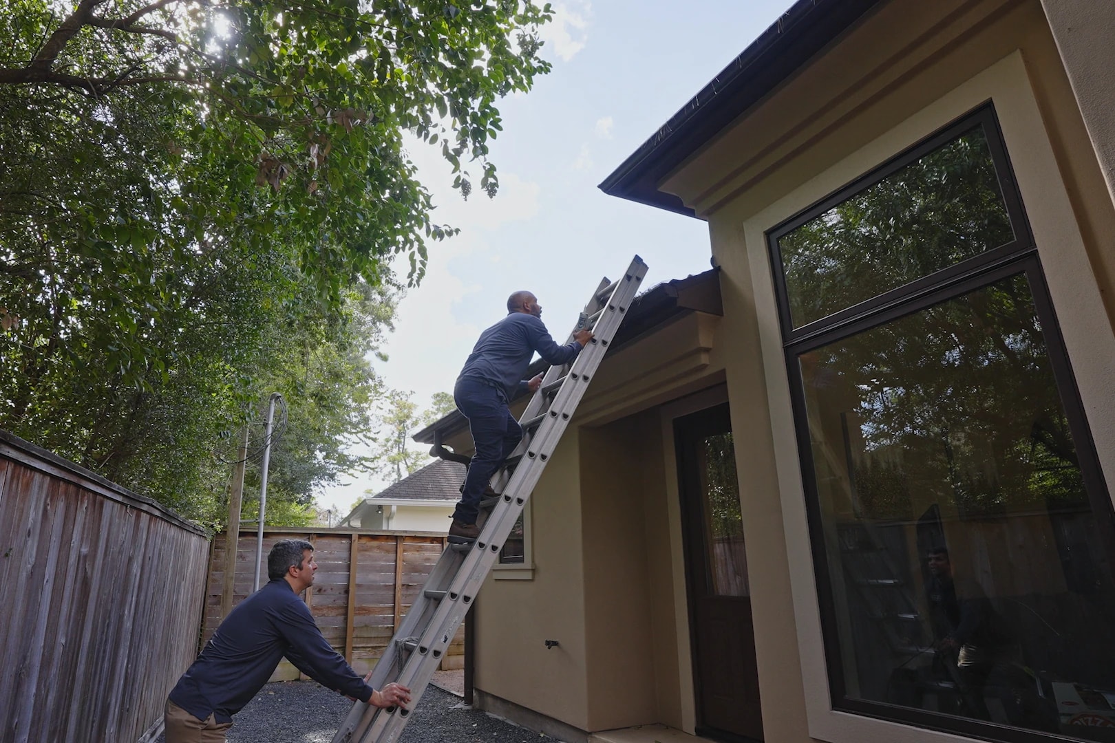 Technicians accessing a roofline to inspect for entry points
