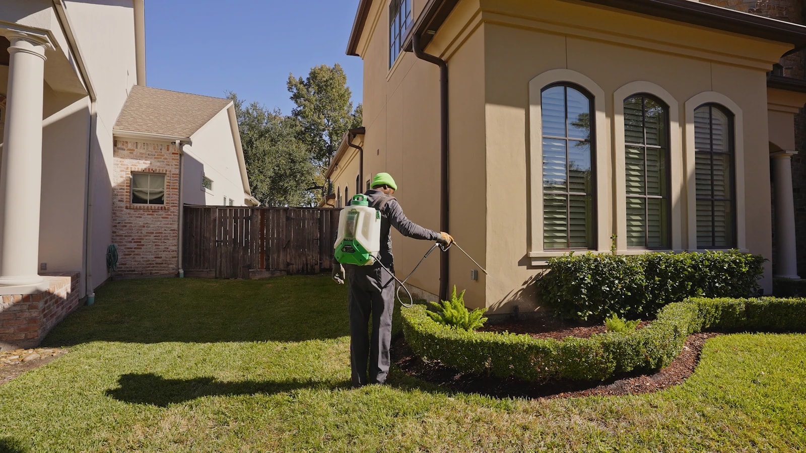 Technician treating along a home's exterior wall