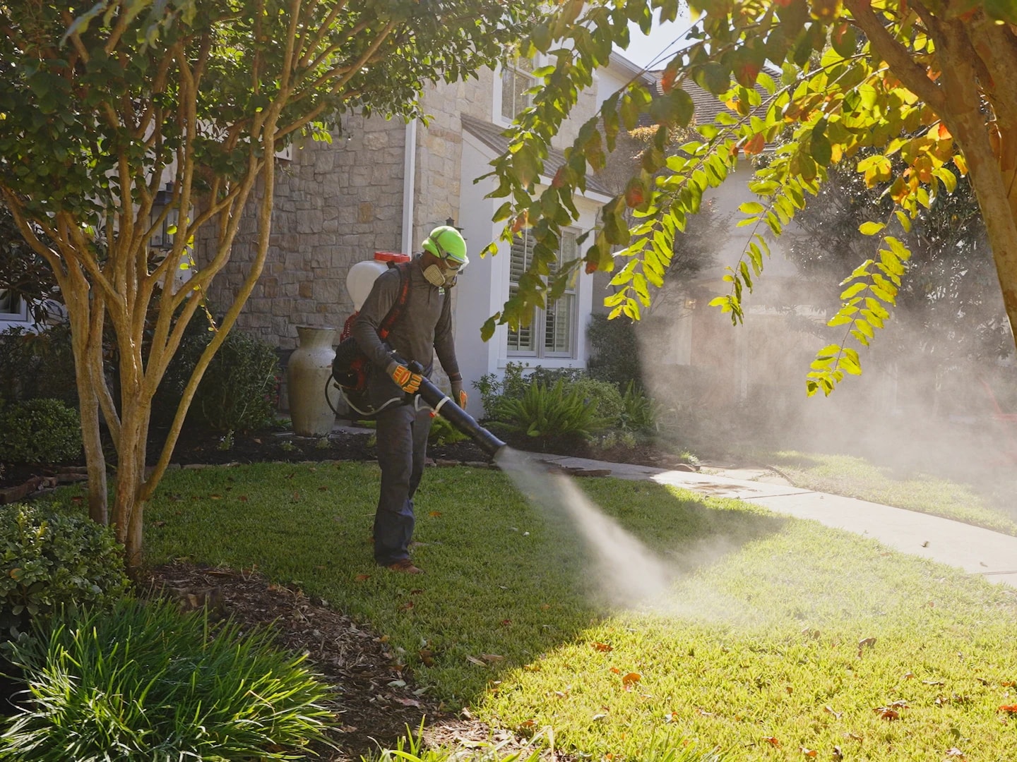 Technician treating the front of a stone-clad home