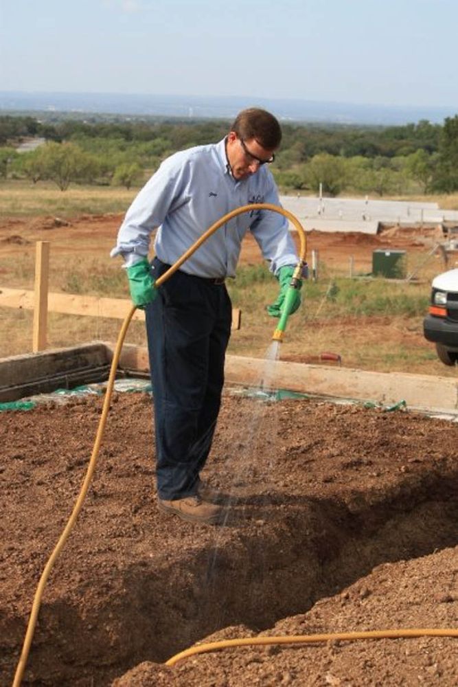 Technician treating soil at a new-construction foundation
